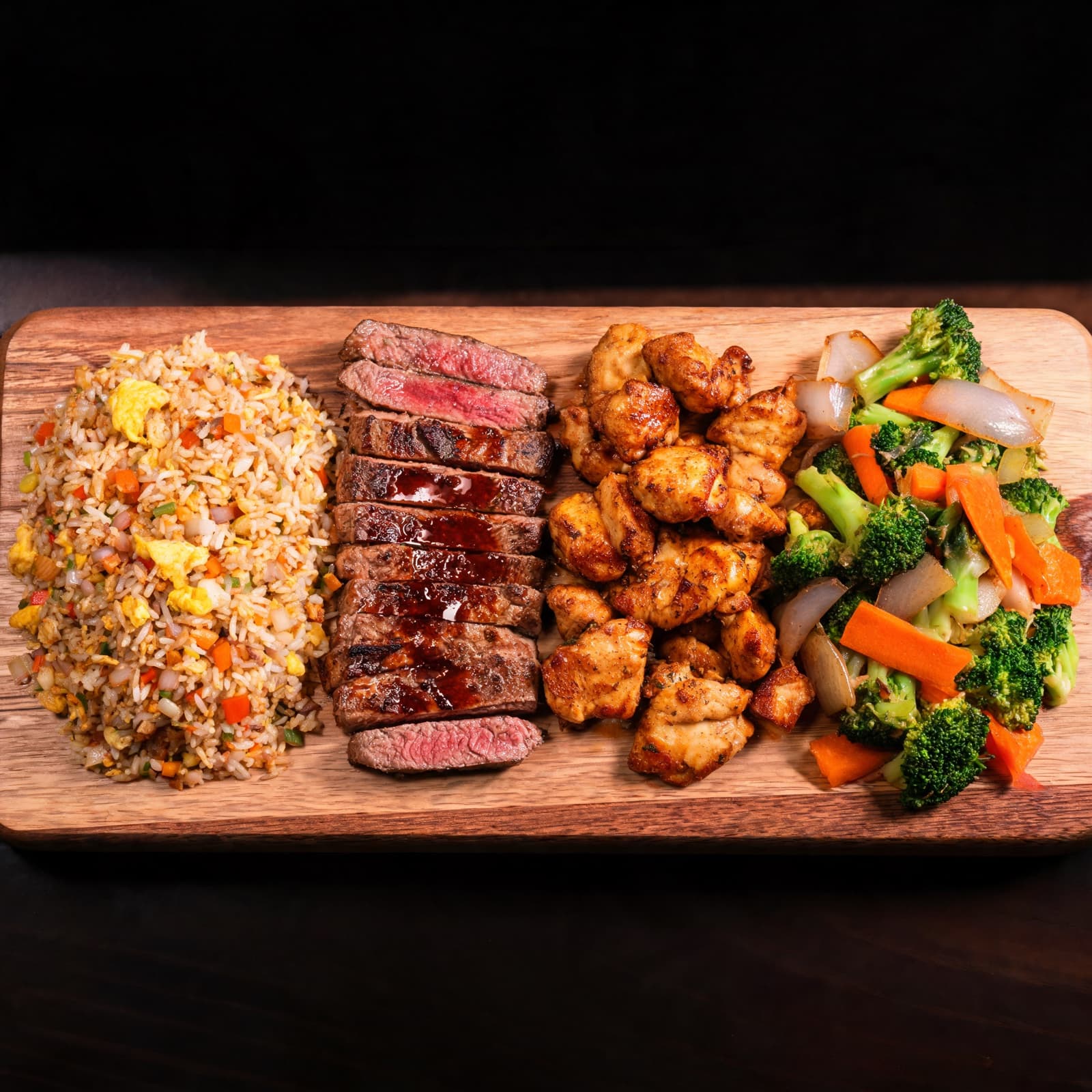 Hibachi feast on a board — fried rice, steak, chicken, and grilled vegetables